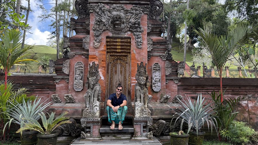 Lucas sentado diante de um templo em Bali